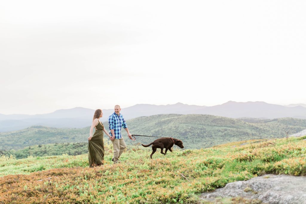 Man and woman and chocolate lab walking up mountain