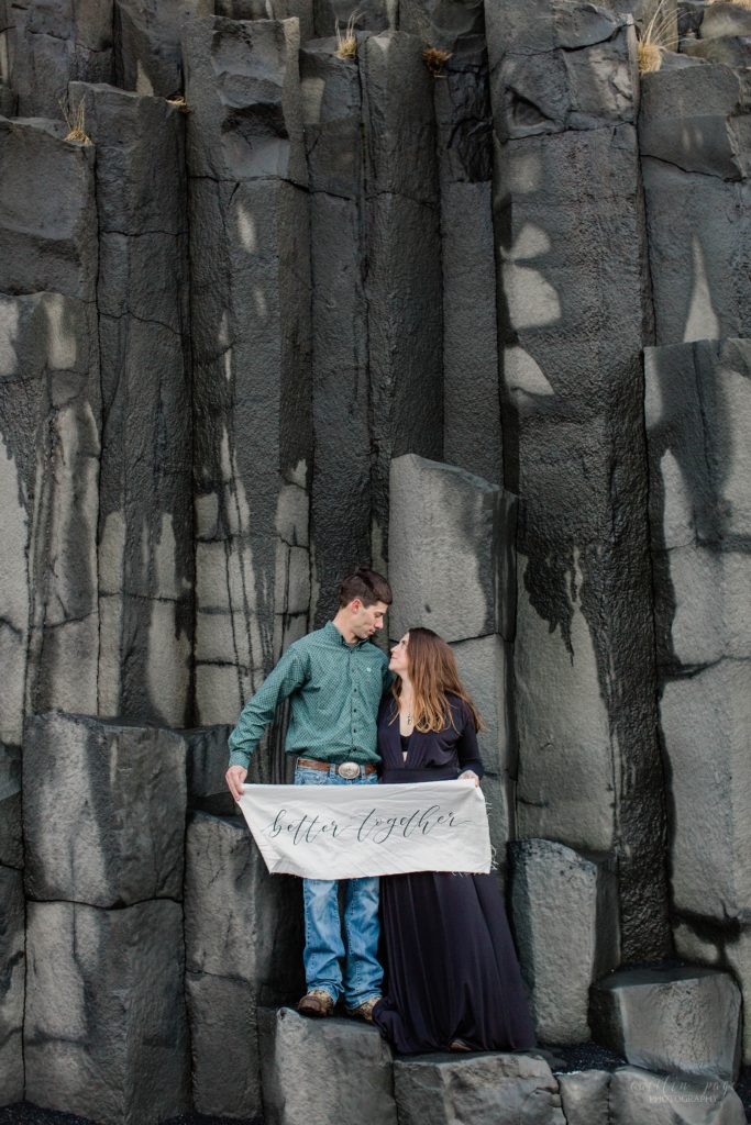 Man and woman standing on black basalt rocks at Reynisfjara Beach in Iceland