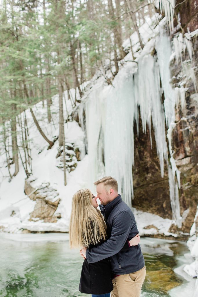 Man and woman kissing in front of frozen waterfall