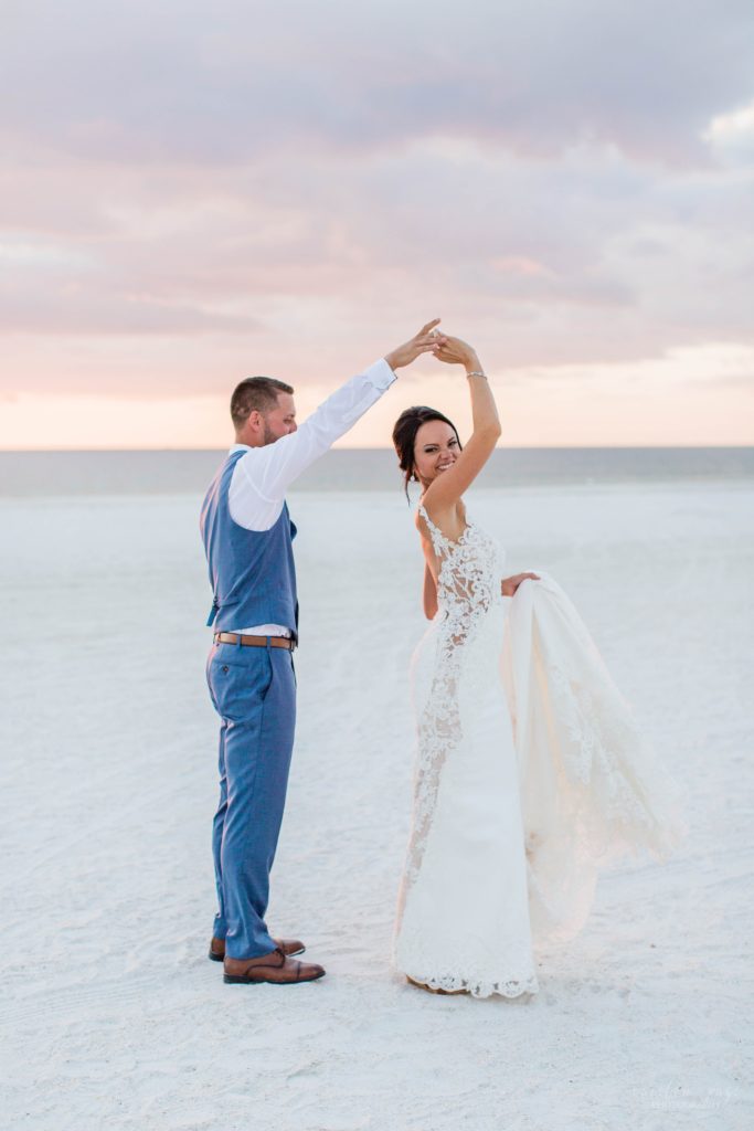 Bride and groom dancing on the beach at sunset