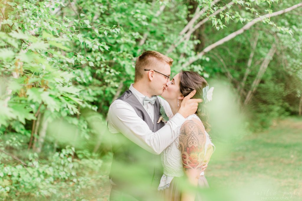 Groom kissing bride through trees
