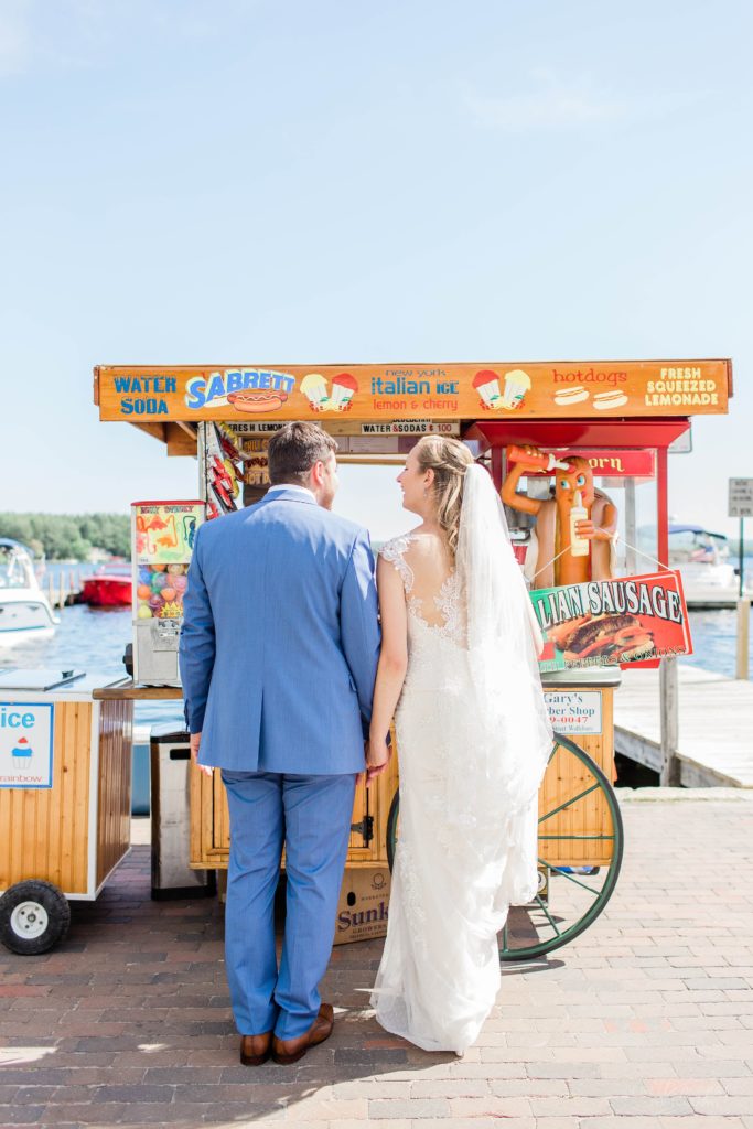 Bride and groom standing in front of a hot dog stand