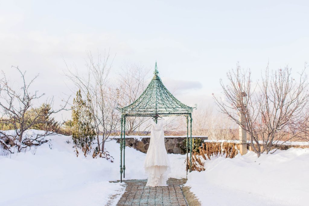 Wedding dress hanging on gazebo with snow