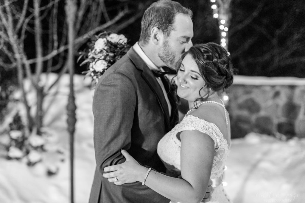 Bride and groom kissing at night with snow