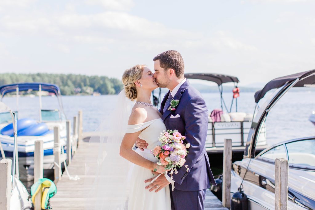 Bride and groom kissing on dock at Brewster Boathouse Wolfeboro