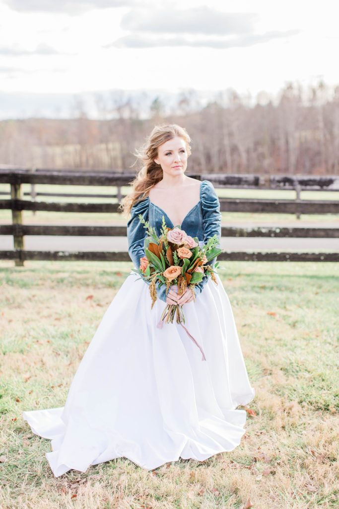 Bride in turquoise bodysuit and white skirt holding bridal bouquet at Mount Ida Farm in Charlottesville Virginia