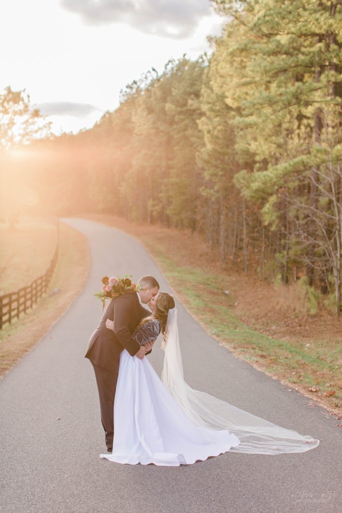 Bride and groom kissing at sunset in front of field of cows at Mount Ida Farm in Charlottesville Virginia