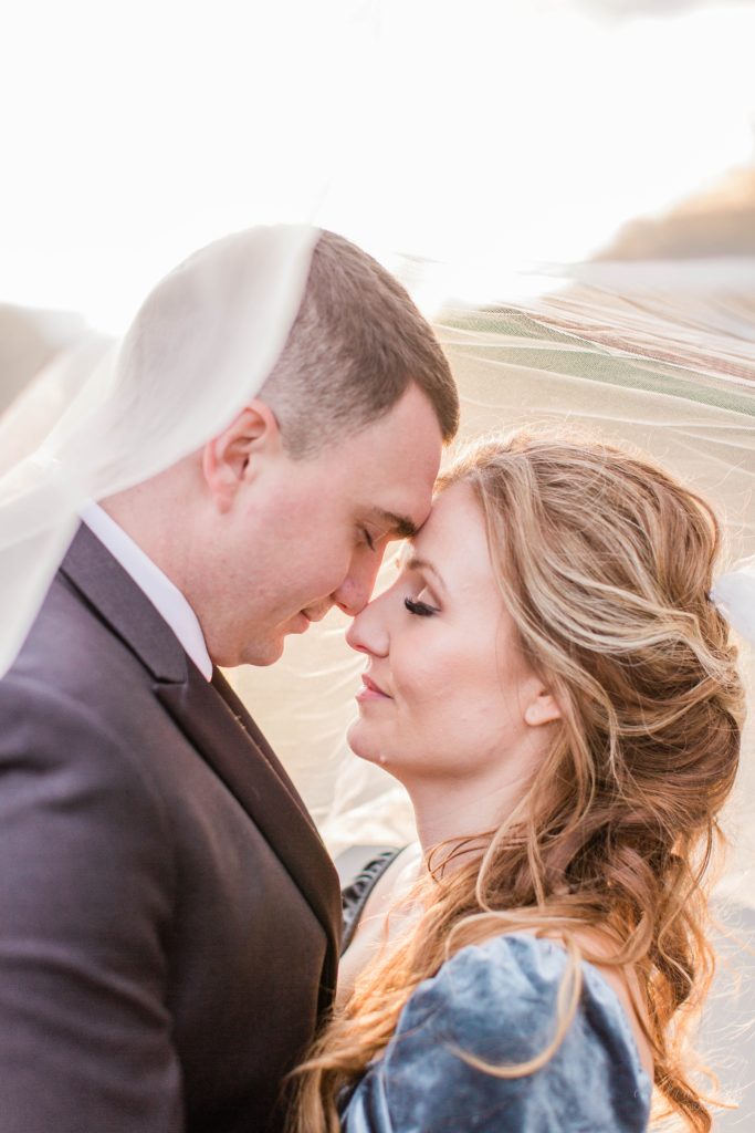 Bride and groom snuggled together under wedding veil at Mount Ida Farm in Charlottesville Virginia