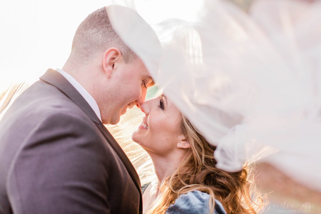 Bride and groom snuggled together under wedding veil at Mount Ida Farm in Charlottesville Virginia