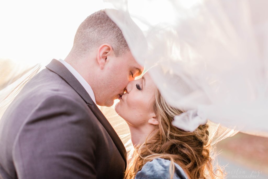 Bride and groom kissing under wedding veil at Mount Ida Farm in Charlottesville Virginia