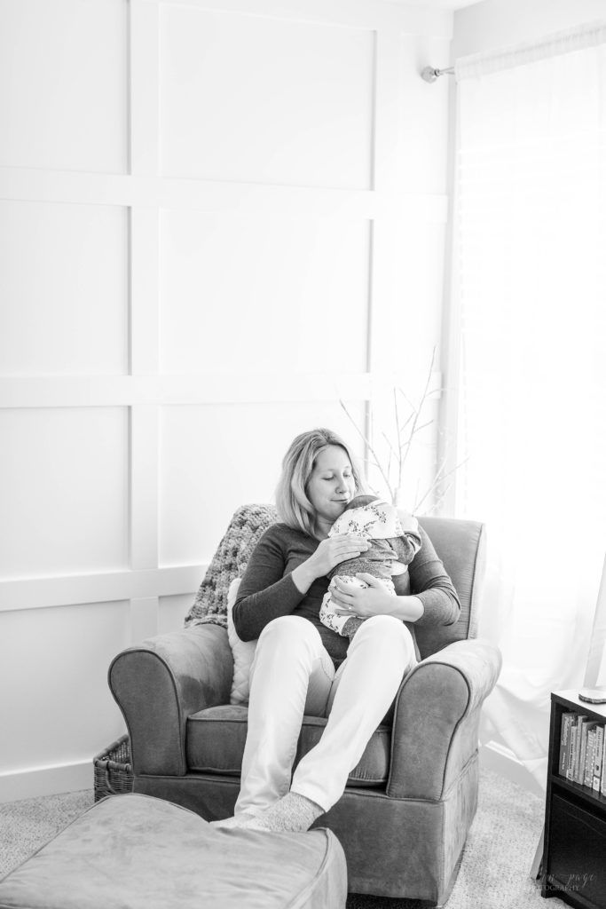 Black and white portrait of mom holding newborn baby girl in her nursery
