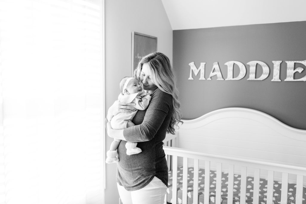 Black and white photo of mom holding newborn baby in her nursery