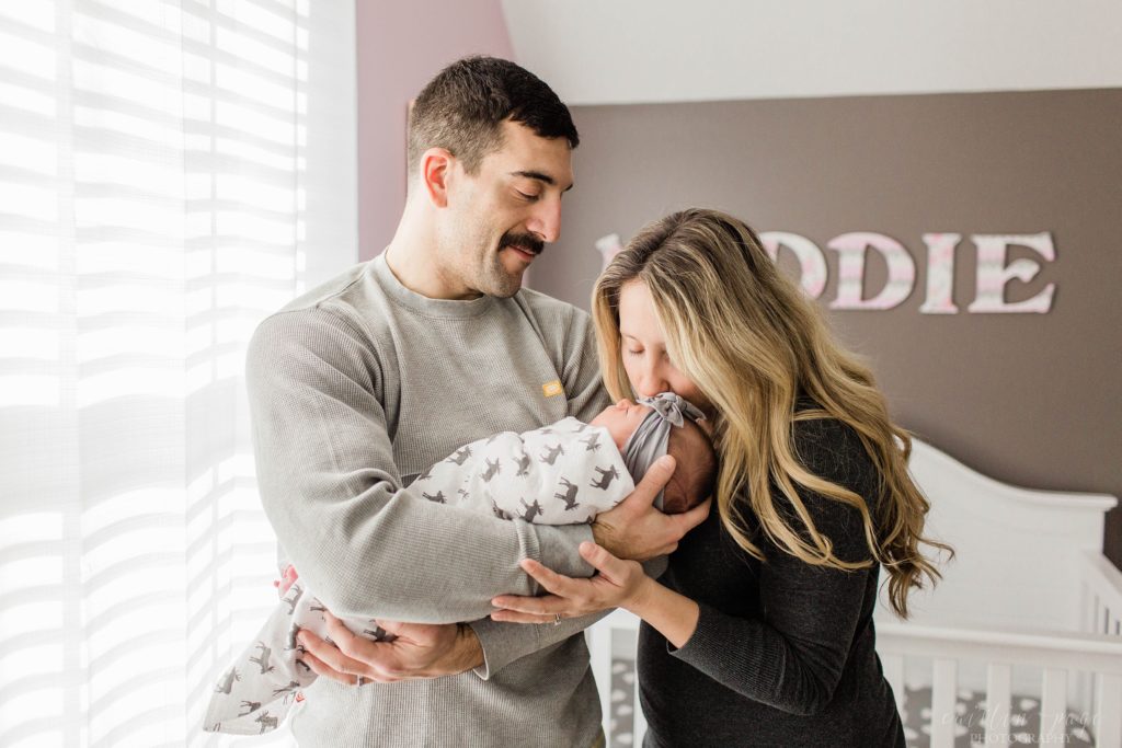 Mom kissing baby while dad holds her