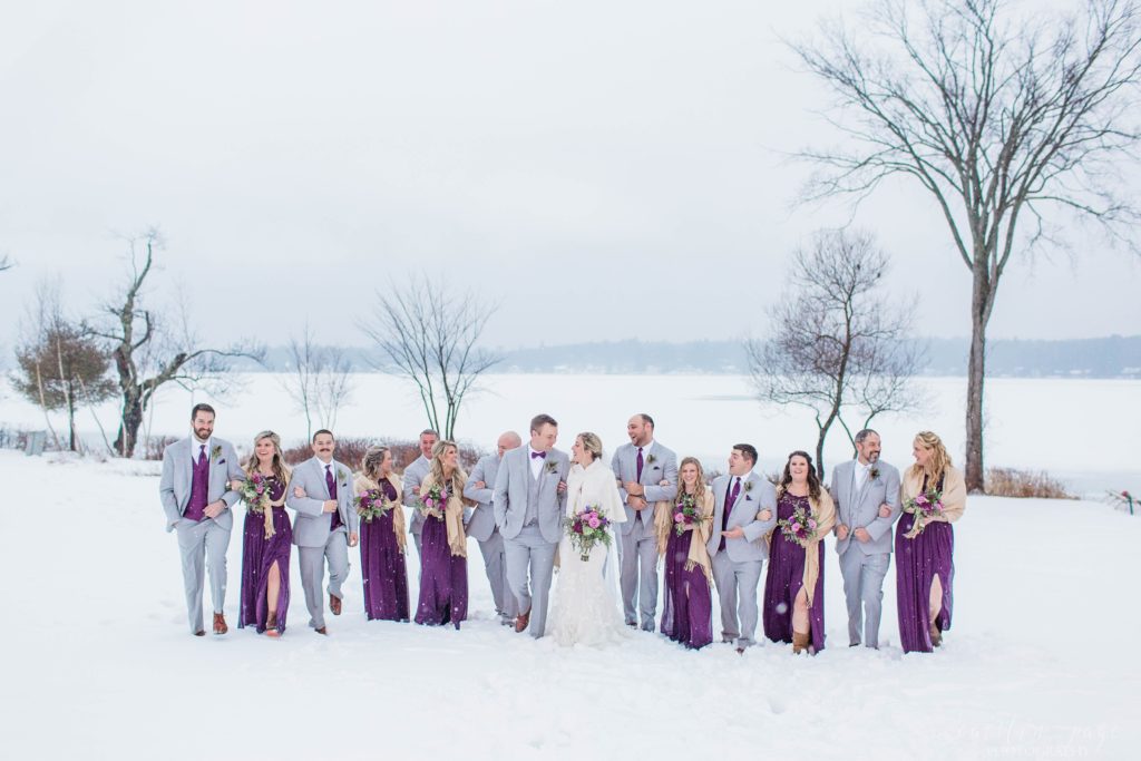 Bridal party standing on lake shore in the snow