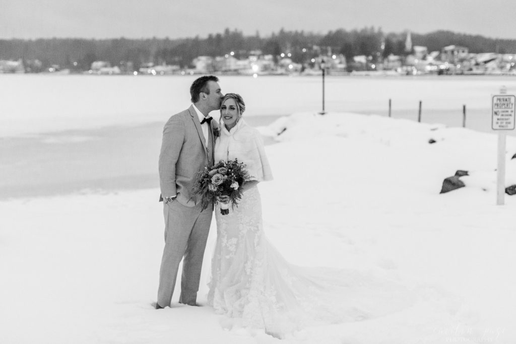 Black and white portrait of bride and groom standing in the snow