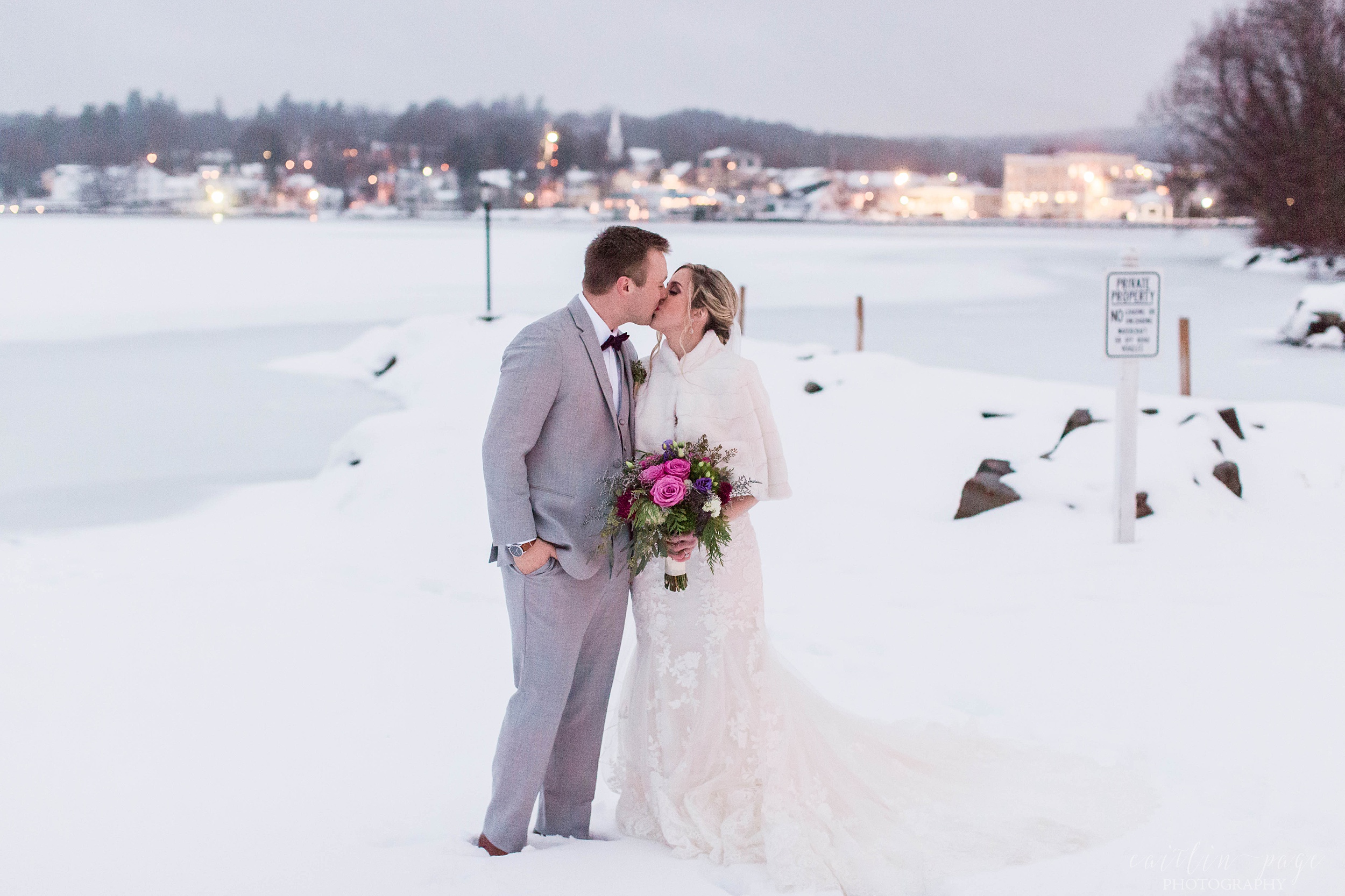 Portrait of bride and groom standing in the snow in front of lake