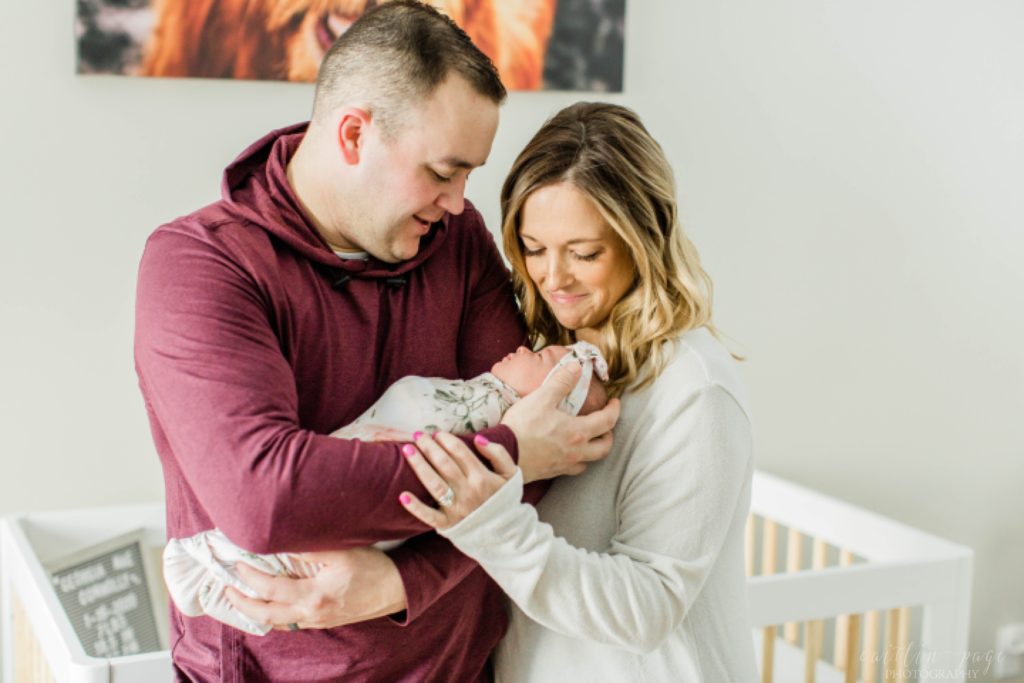 Mom and dad holding newborn baby girl in floral swaddle