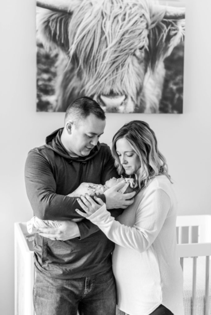 Mom and dad holding newborn baby girl in floral swaddle
