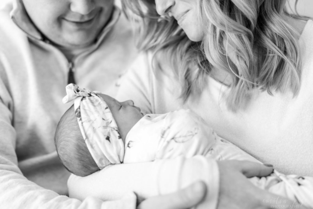 Black and white portrait of mom and dad holding newborn baby girl