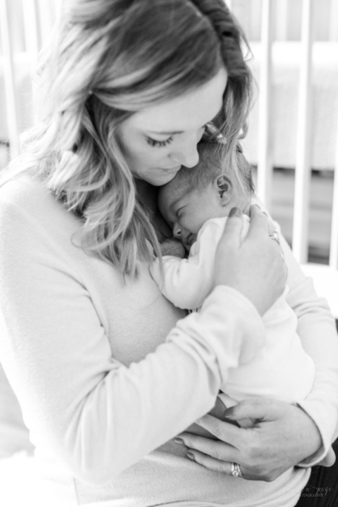 Black and white photo of mom snuggling newborn baby girl to her chest