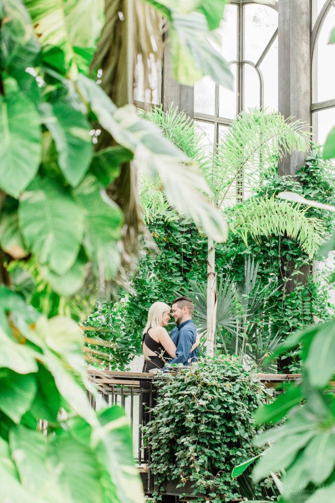 Man and woman laughing at each other through tropical trees at Longwood Gardens