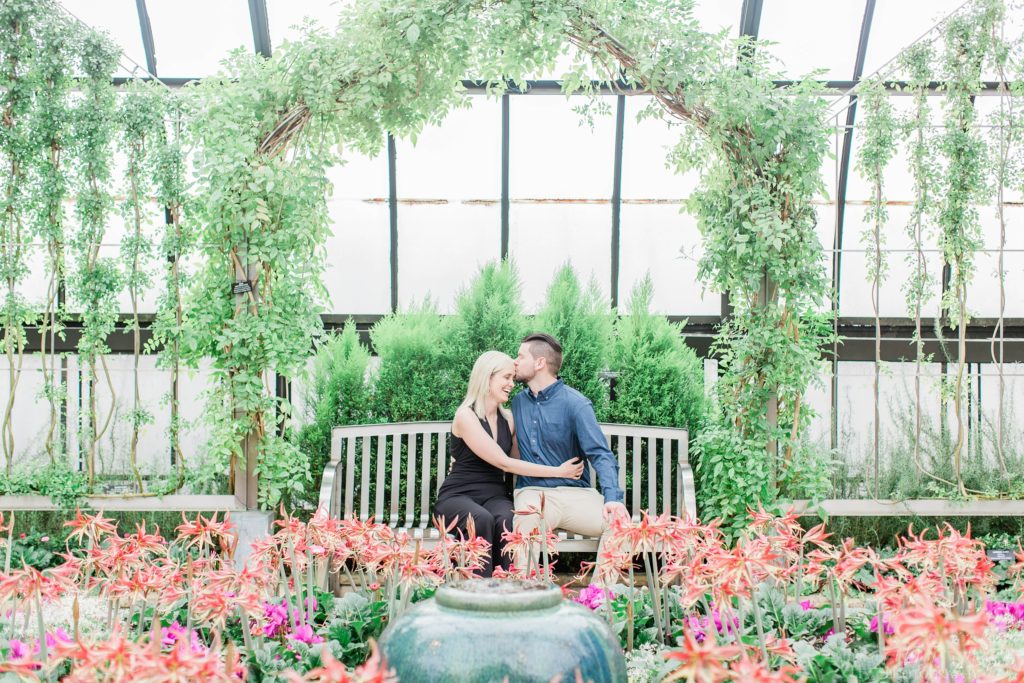 Man and woman sitting together on bench in middle of floral display at Longwood Gardens