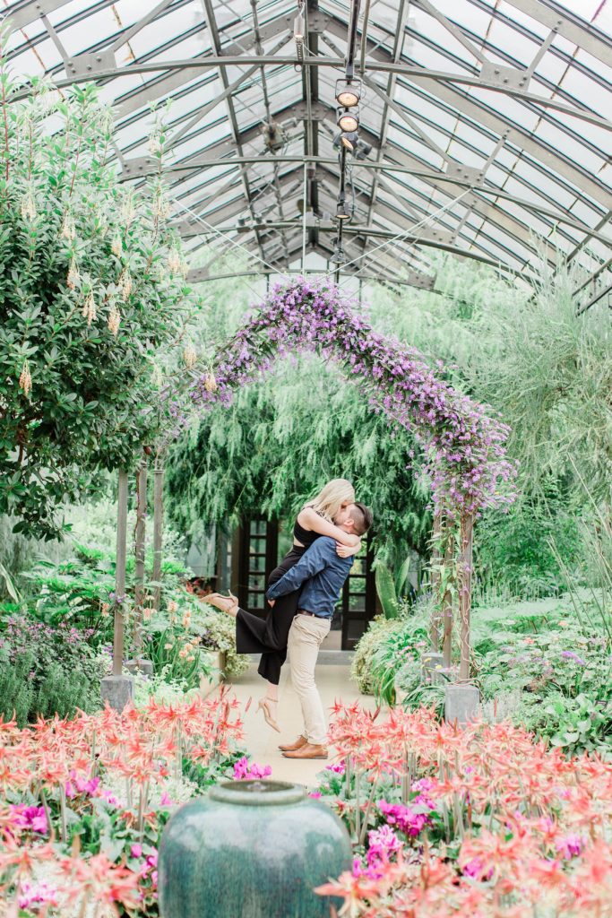 Man lifting woman into the air and kissing her in front of floral display at Longwood Gardens