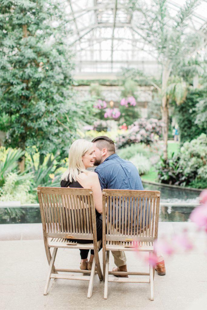 Man and woman sitting together in front of hall of floral display at Longwood Gardens