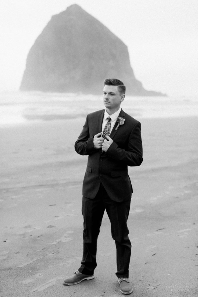 Black and white portrait of groom standing on Cannon Beach
