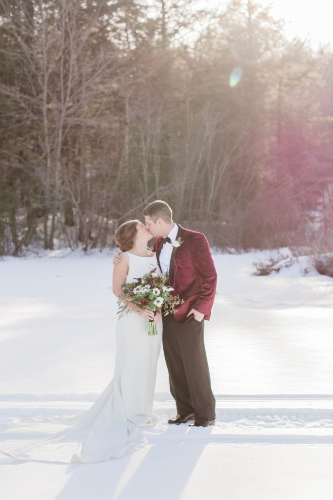 Wedding couple kissing on frozen Lake Winnipesaukee in Wolfeboro New Hampshire