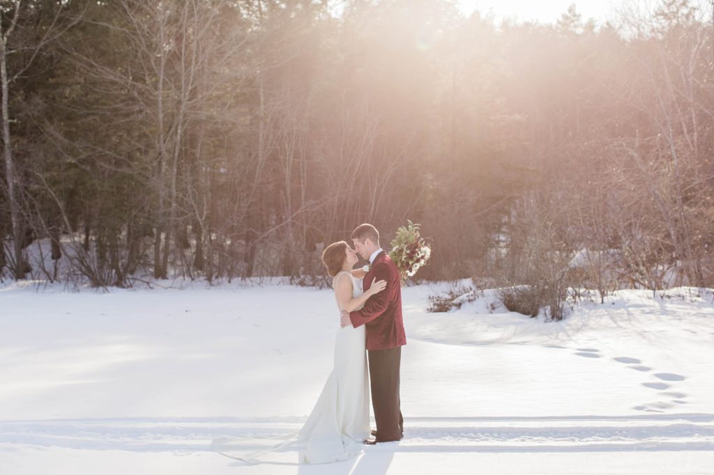 Wedding couple kissing on frozen Lake Winnipesaukee in Wolfeboro New Hampshire