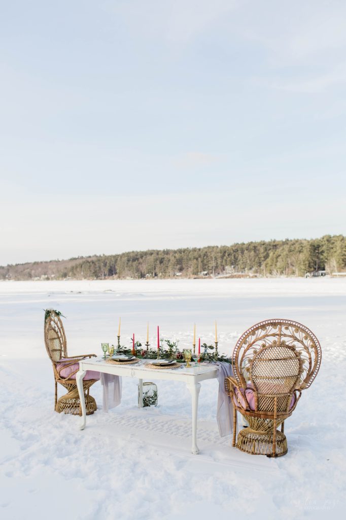 Styled wedding reception table with peacock chairs on frozen lake