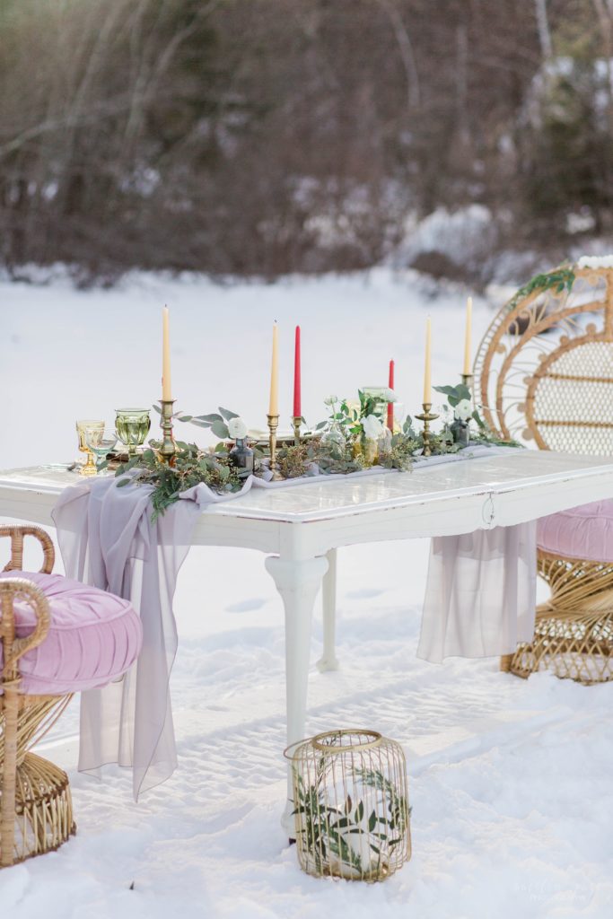 Styled wedding reception table with peacock chairs on frozen lake