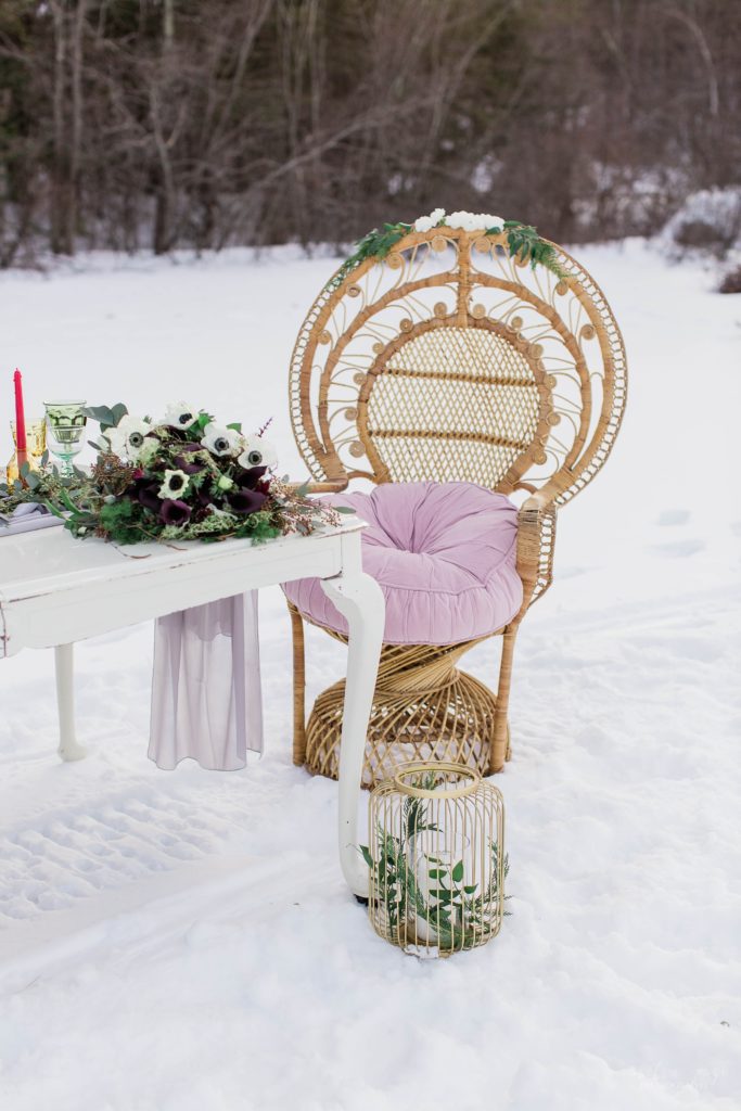 Styled wedding reception details with peacock chair on frozen lake