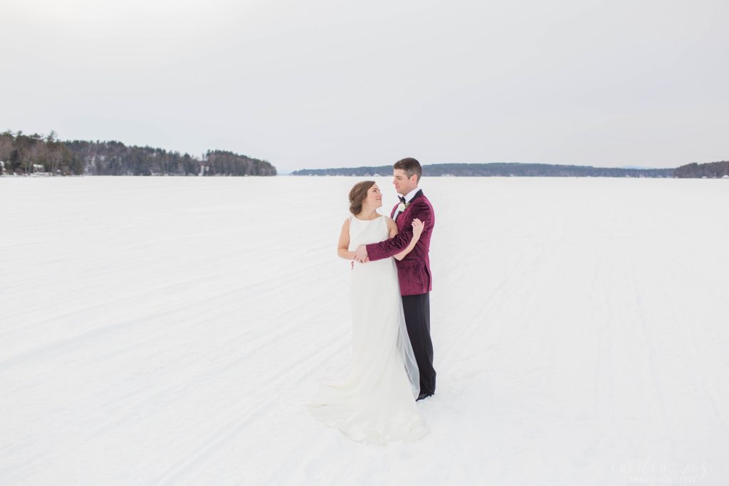 Bride and groom snuggled together in the middle of a frozen lake