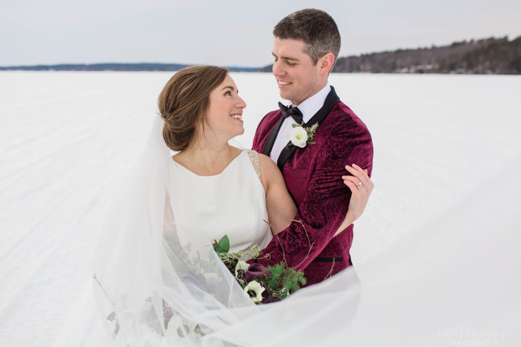 Bride and groom snuggled together in the middle of a frozen lake
