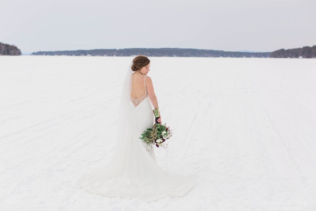 Bride wearing backless wedding dress standing in middle of frozen lake
