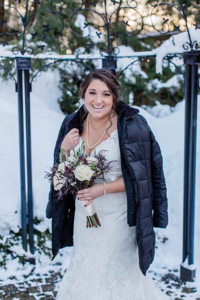 Winter bride standing in courtyard wearing winter coat