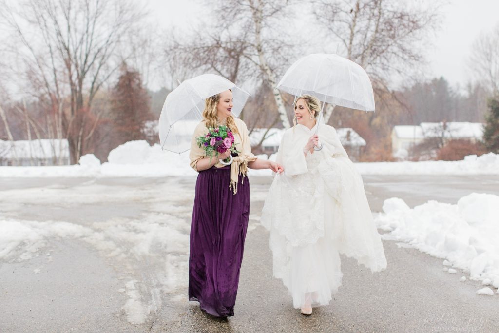 Bride and bridesmaid walking together with clear umbrellas