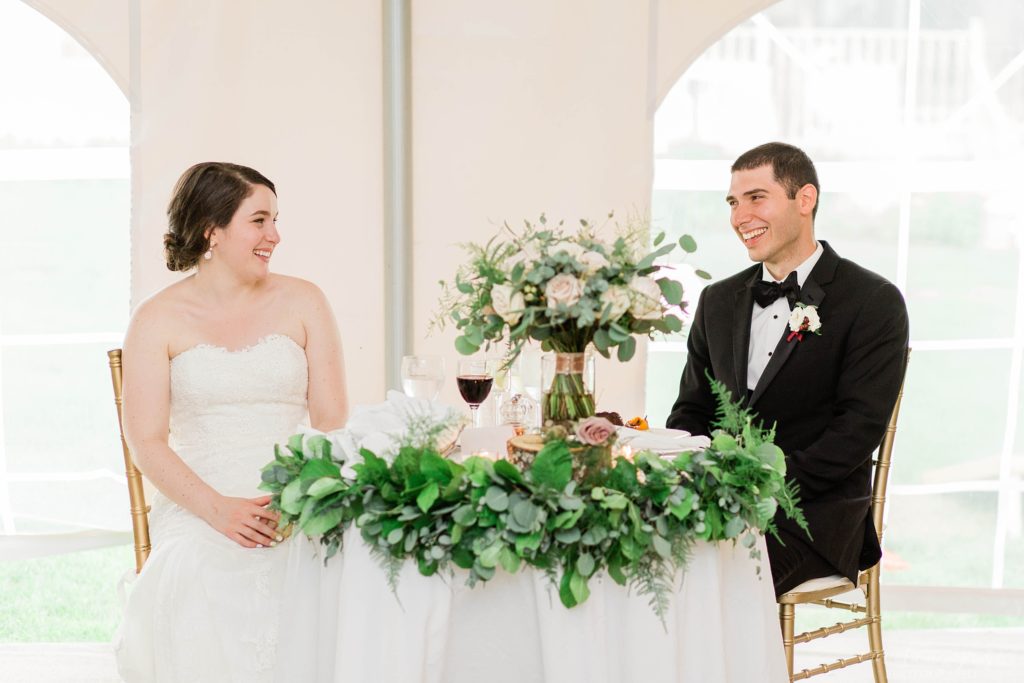 Couple sitting in reception tent at sweetheart table