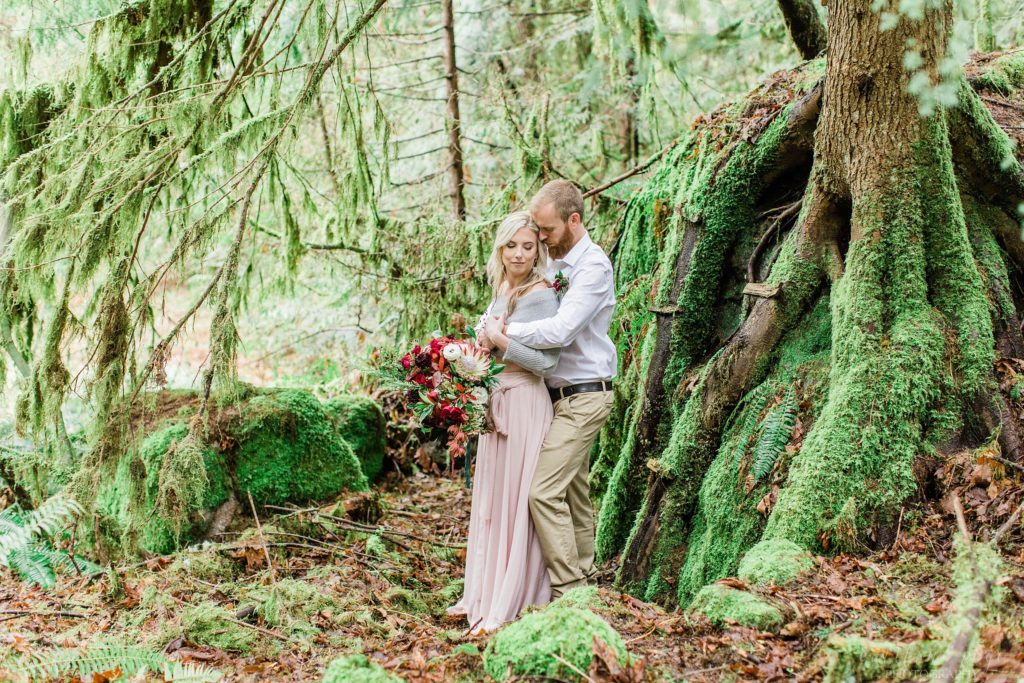 Man and woman snuggled together in the woods during romantic elopement