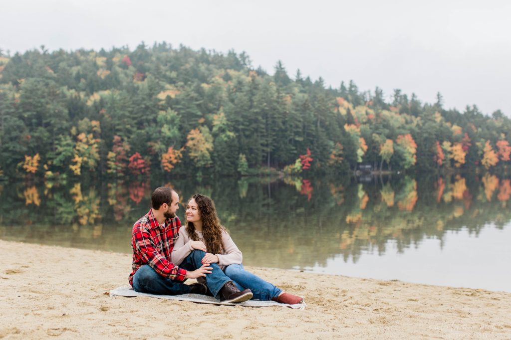 Mn and woman sitting together on beach during fall colors