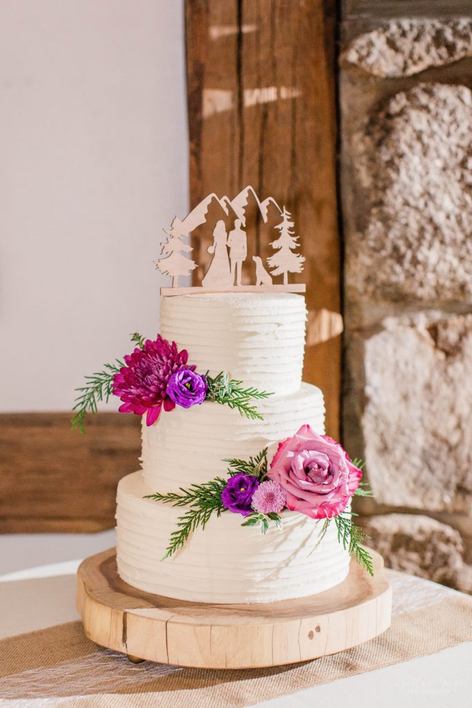 Three tiered white wedding cake with pink and purple flowers