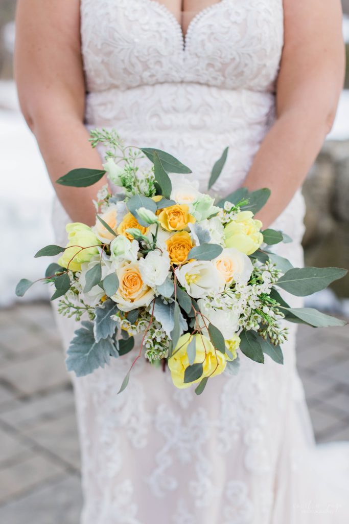 Small wedding bouquet being held by bride with pops of yellow and orange