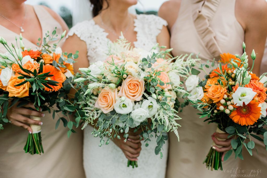 Bride and bridesmaids holding bouquets with orange daisies