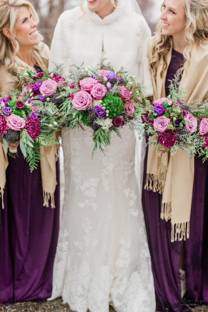Winter bride and bridesmaids holding purple and pink bouquets