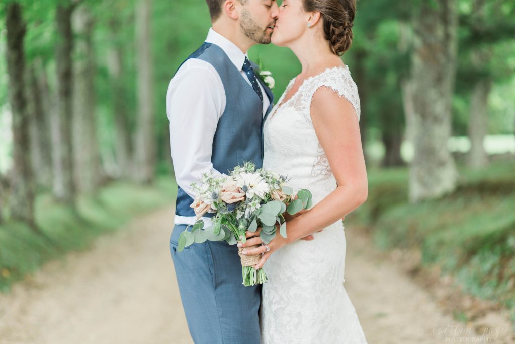 Bride and groom kissing holding wedding bouquet