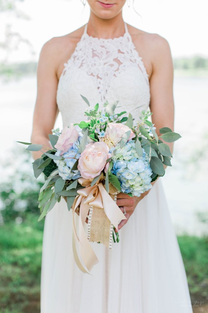 Bride holding wedding bouquet with blue hydrangeas and pink roses