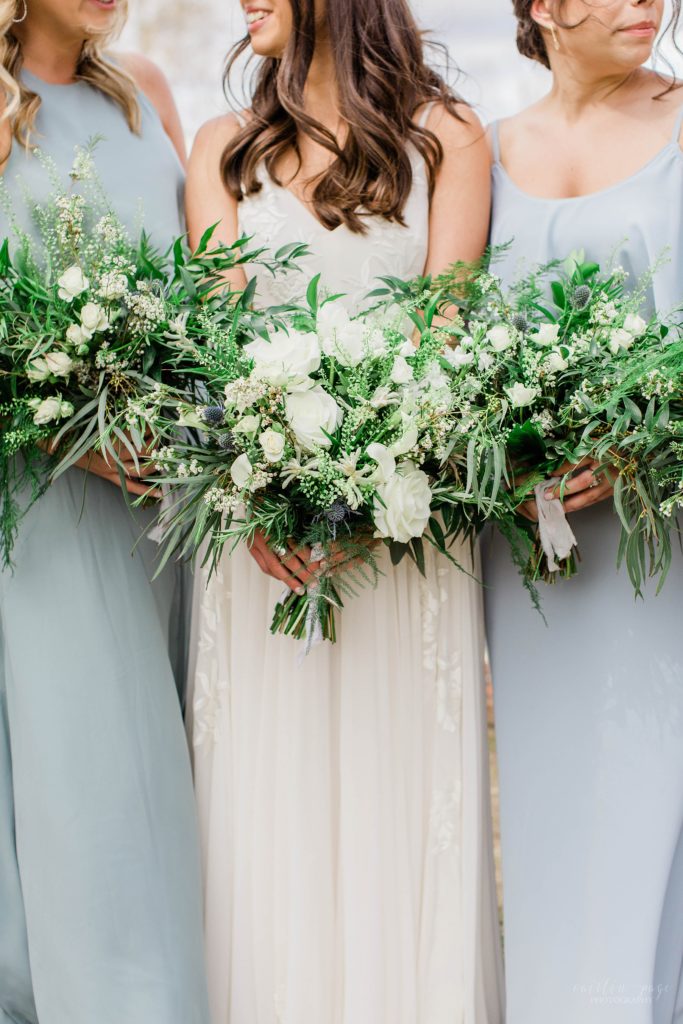Bride and bridesmaids holding textured bouquets with greens and white floral accents