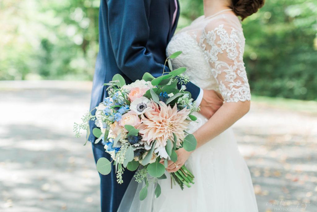 Bride and groom kissing with textured wedding bouquet with anemones and lisianthus